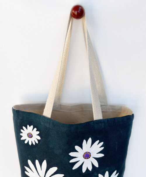white chamomile on navy blue tote bag top view