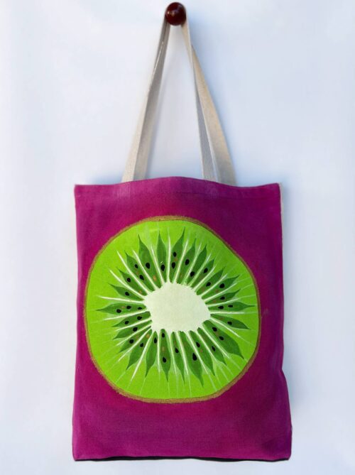 Green kiwi on pink background tote bag front view hanging