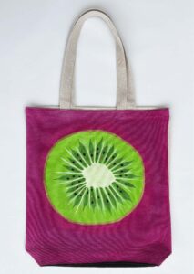 Green kiwi on pink background tote bag