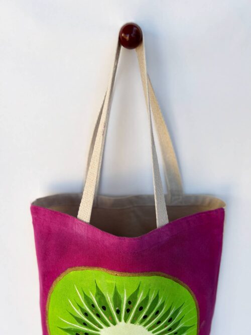 Green kiwi on pink background tote bag top view hanging