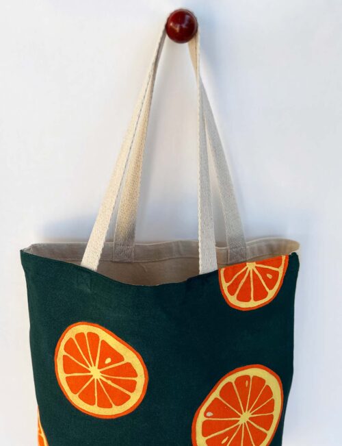 oranges on dark green background tote bag top view